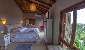 um quarto com uma cama e uma porta de vidro deslizante em Pousada Bangalôs do Rosa-Praia do Rosa na Praia do Rosa