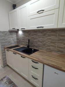a kitchen with white cabinets and a sink at Apartman Front in Šid