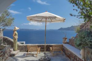 a woman in a hat standing next to an umbrella at Oia Waves Cave Houses in Oia +12 photos