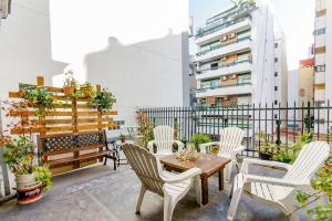 un patio con sillas blancas y una mesa en el balcón en Baires House en Buenos Aires