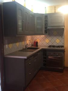 una cucina con mobili bianchi, un lavello e una stufa di Maison de village dans joli hameau médiéval a La Tour-sur-Orb