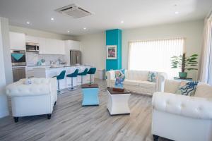 a living room with white furniture and a kitchen at The Cove - Condo Hotel - Palm Beach Strip in Palm-Eagle Beach