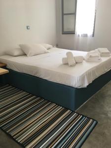a bed with white sheets and towels on it at Cristi Rooms in Livadion