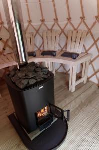 a wood fired stove in a room with two chairs at Eastside Byre - Family cottage in the Pentland Hills near Edinburgh in Penicuik
