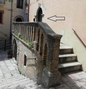 un muro di pietra accanto a un edificio con scala di Valerio's Home Historical Center a Larino
