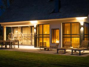 a house with a patio with chairs and tables at night at Luxury villa with sauna near beach in De Cocksdorp