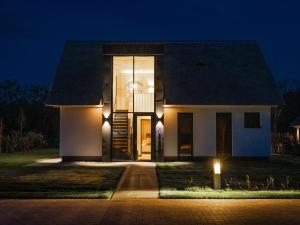 a house with lights on the side of it at night at Luxury villa with sauna near beach in De Cocksdorp