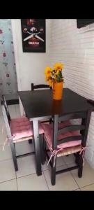 a black table with a vase of yellow flowers on it at Solar da Suzi in Praia do Rosa