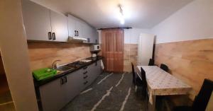 a kitchen with white cabinets and a sink and a table at Marcy Lux in Baile Felix