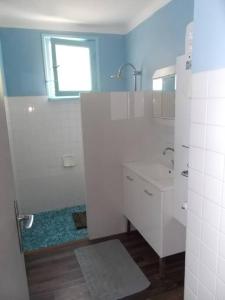 La salle de bains blanche est pourvue d'un lavabo et d'une fenêtre. dans l'établissement Kerleuquer Ty Nevez, à Plobannalec-Lesconil