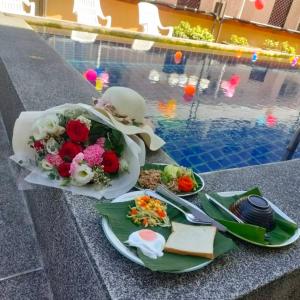 a table with flowers and food next to a pool at Pailin Hill Hotel in Patong Beach