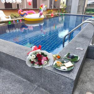 einen Tisch mit einem Blumenstrauß neben einem Pool in der Unterkunft Pailin Hill Hotel in Patong Beach