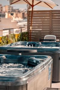a couple of hot tubs with an umbrella at Grands Suites Hotel Residences and Spa in Il-Gżira