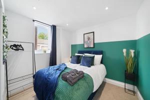 ブリストルにあるBristol Short Stays Brislington Sleeps 4-9 Free Parkingの青と緑の壁のベッド1台が備わるベッドルーム1室が備わります。