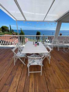 - une table et des chaises blanches sur une terrasse donnant sur l'océan dans l'établissement Sunrise SeaView Apartment Fiesa, à Piran