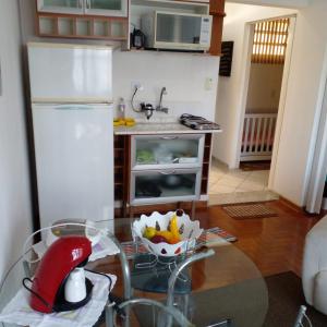 uma cozinha com uma mesa de vidro e um frigorífico branco em Apartamento 2 dormitórios, wifi, ponta da praia, predio em frente ao mar - Santos em Santos