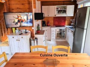 Cabaña con cocina con mesa y TV. en A BIAS Chalet 4 à 6 Personnes Entièrement Climatisé Chargeur VE 7kw-Wifi-Balnéo et Piscine en Bias