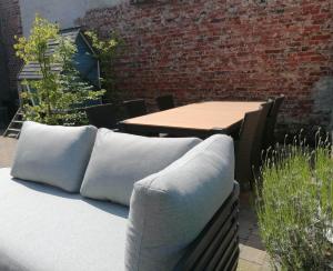 un patio con almohadas, una mesa y una pared de ladrillo en Maison Miest, en Watou