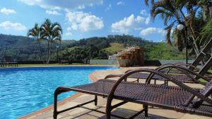 a swimming pool with a bench next to the water at Pousada Costa Rielli in Águas de Lindoia