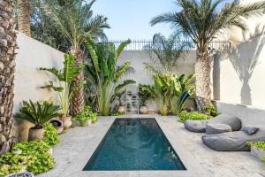 a swimming pool in a courtyard with palm trees at Hotel Anilevich Mansion in Beer Sheva