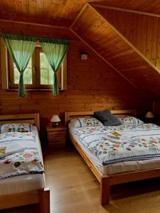 two beds in a log cabin with two windows at Penzión Driečna in Havaj