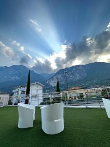 d'un balcon avec des chaises blanches et une vue sur les montagnes. dans l'établissement Athos Hotel, à Riva del Garda