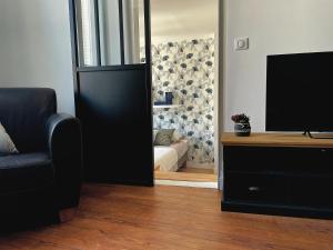 ein Wohnzimmer mit einem TV und einem Sofa in der Unterkunft Appartement cosy et lumineux centre-ville #4 in Dreux