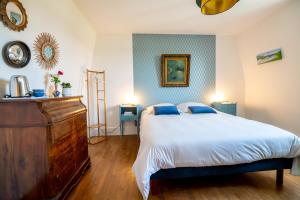 a bedroom with a large bed and a dresser in it at Le Clos Eugénie in Gennes