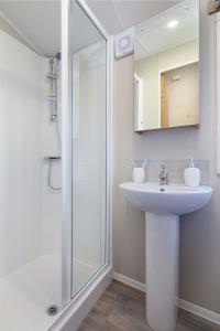 a white bathroom with a sink and a shower at Springwood Holiday Park in Kelso