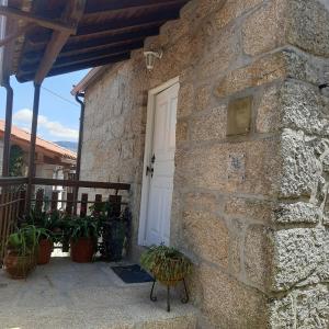 a stone house with a white door and plants at Casa de Bairros in Soajo