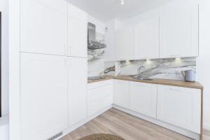 Una cocina blanca con gabinetes blancos y un fregadero. en Apartament Perłowy z Basenem Letnim by HolidaySun, en Sianożęty