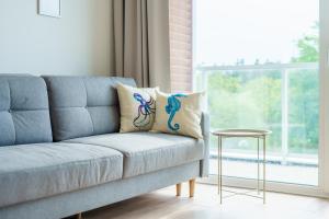 Sofá azul en la sala de estar con ventana en Apartament Perłowy z Basenem Letnim by HolidaySun, en Sianożęty