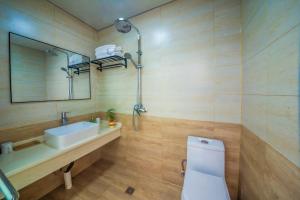W łazience znajduje się toaleta, umywalka i lustro. w obiekcie Yixun Inn w mieście Zhangjiajie