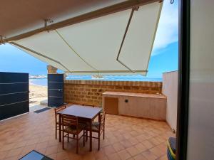 Blick auf eine Terrasse mit einem Tisch und Stühlen in der Unterkunft Appartamento Liam in Marzamemi