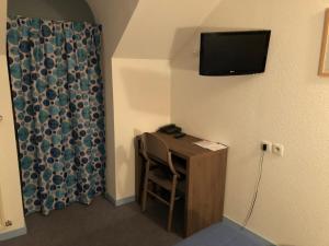 um quarto com uma secretária e uma televisão na parede em HOTEL DE LA GARE em Eygliers
