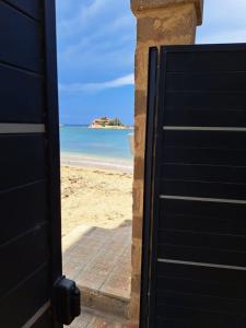 eine offene Tür zu einem Strand mit dem Meer in der Unterkunft Appartamento Liam in Marzamemi