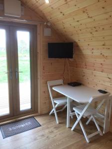 a room with a table and a television in a cabin at Wall Eden Farm - Luxury Log Cabins and Glamping in Highbridge