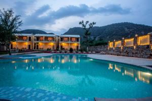 uma piscina num resort com montanhas ao fundo em Ratan Villas Sariska em Alwar