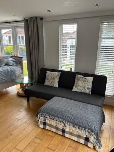 a living room with a black couch and a table at Lovely studio cabin. Hot tub ex £40 per night in Poole