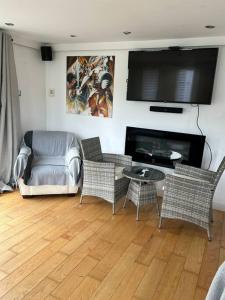 sala de estar con mesa, sillas y TV de pantalla plana. en Lovely studio cabin. Hot tub ex £40 per night, en Poole