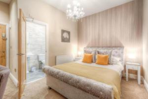 1 dormitorio con 1 cama con almohadas de color naranja y lámpara de araña en The George Wright Boutique Hotel, Bar & Restaurant, en Rotherham