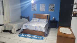 a bedroom with two beds and blue walls at ACONCHEGO DE CANELA/RS in Canela