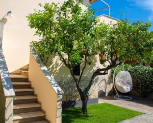 uma árvore ao lado de uma casa com escadas em Roussev Apartment - Coastal Gem - Anzio em Anzio