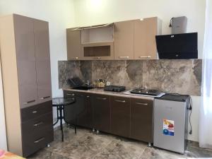 a kitchen with brown cabinets and a stove top oven at Burj-Gala in Kobuleti