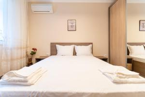 um quarto com uma cama grande e lençóis brancos em City center 2-Bedroom Apartment em Plovdiv