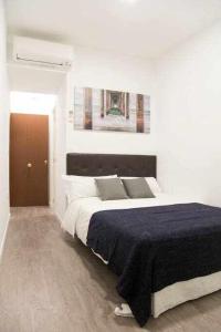 マドリードにあるComodo Y Agradable Apartamento En Madrid Centro 5の白いベッドルーム(青い毛布付きのベッド付)