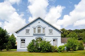 a white house with bushes in front of it at Villa Fokken Bootsmannsquartier in Esens