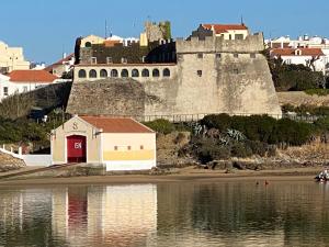 un castello situato in cima a una collina vicino a uno specchio d'acqua di Casa das Marias a Vila Nova de Milfontes
