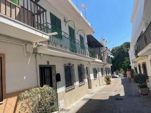 a narrow street with a building with green shutters at Casa Calderón in Marbella