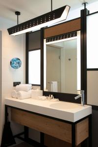 La salle de bains est pourvue d'un lavabo et d'un grand miroir. dans l'établissement Aloft Strasbourg Etoile, à Strasbourg